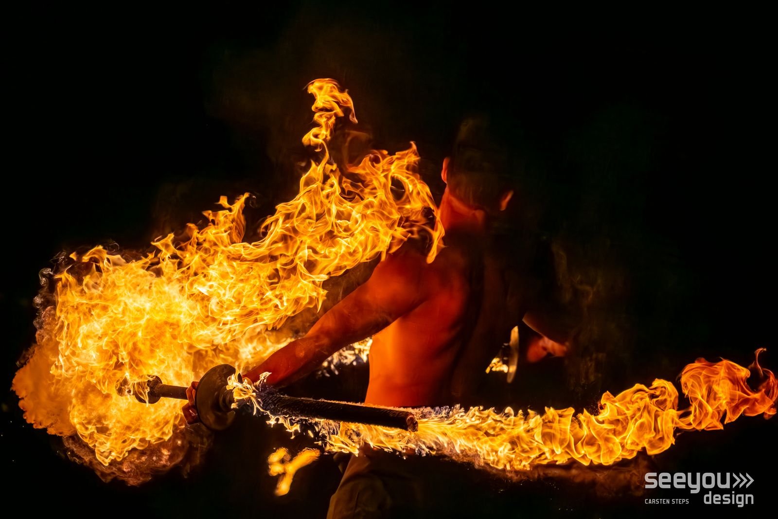 Srikanta Barefoot spinning double fire swords, trailing wide arcs of flame